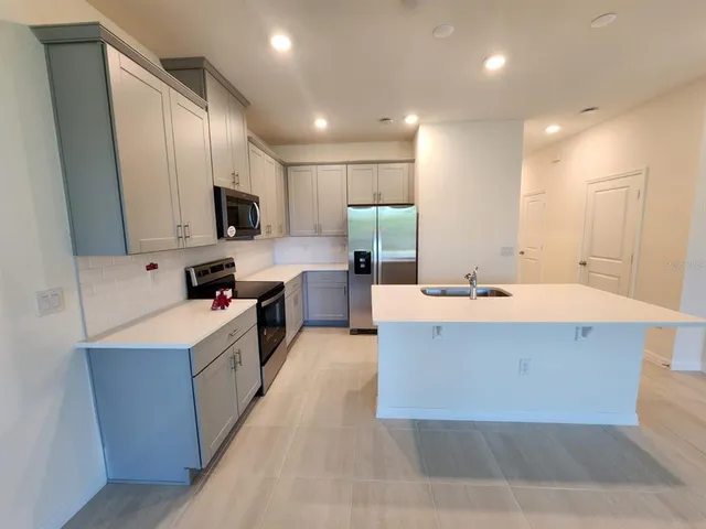 a kitchen with kitchen island a sink a stove a refrigerator and cabinets