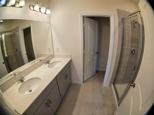 a spacious bathroom with a double vanity sink a mirror and a shower