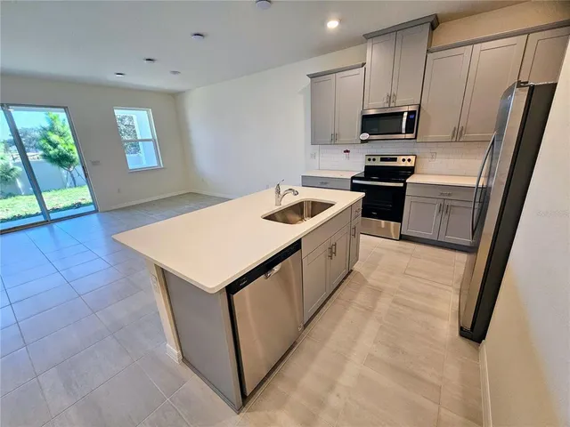 a large kitchen with kitchen island a sink a counter top space stainless steel appliances and cabinets