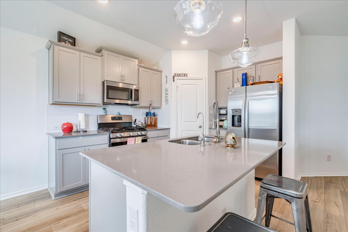 389 Salt Springs Road Kyle, TX 78640 - Photo 10 of 30 Sleek stainless steel appliances complement the light grey cabinetry and central island, perfect for casual dining.
