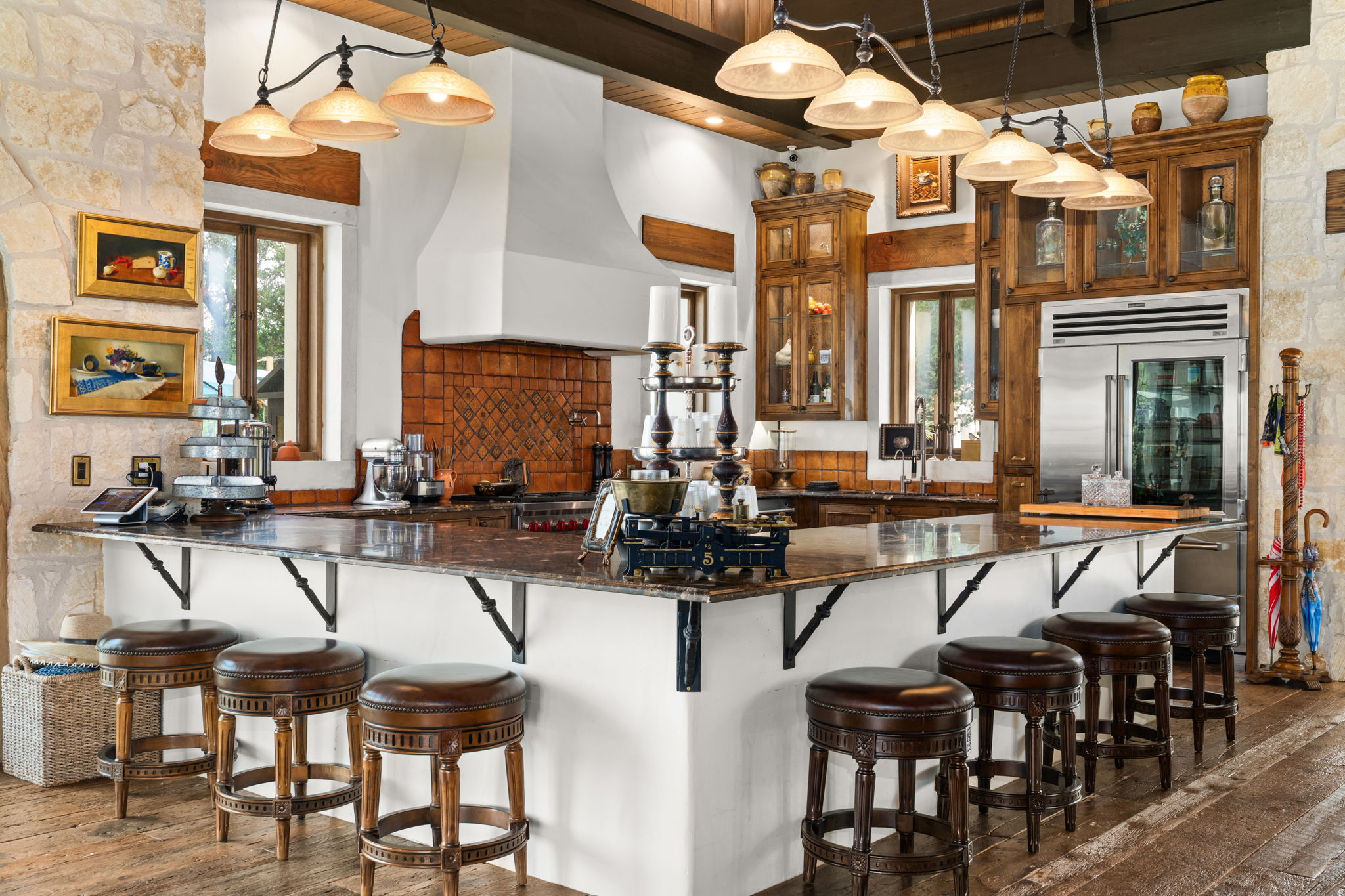 11941 Overlook Pass Austin, TX 78738 - Photo 38 of 40 Spacious kitchen featuring an expansive island with seating, stainless steel appliances, a tiled backsplash, exposed wood beam ceiling, and custom wood cabinetry