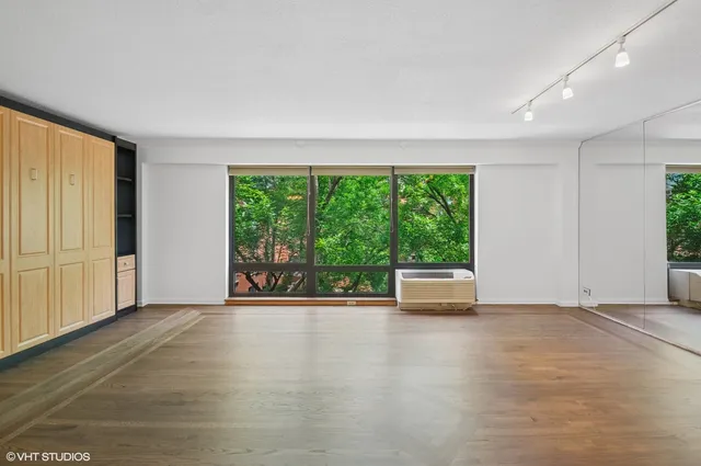 a view of an empty room with wooden floor and windows