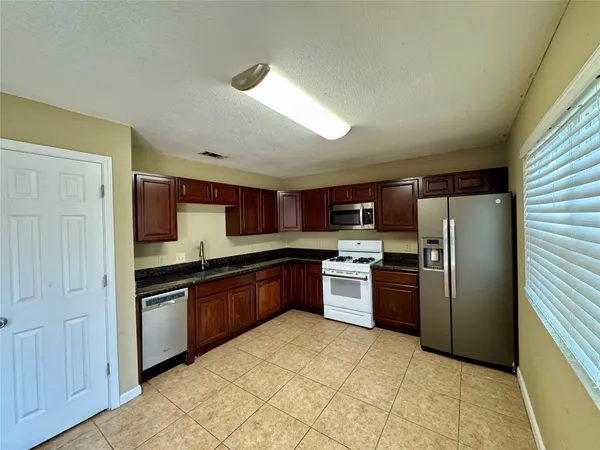 a kitchen with stainless steel appliances granite countertop a refrigerator and a stove top oven