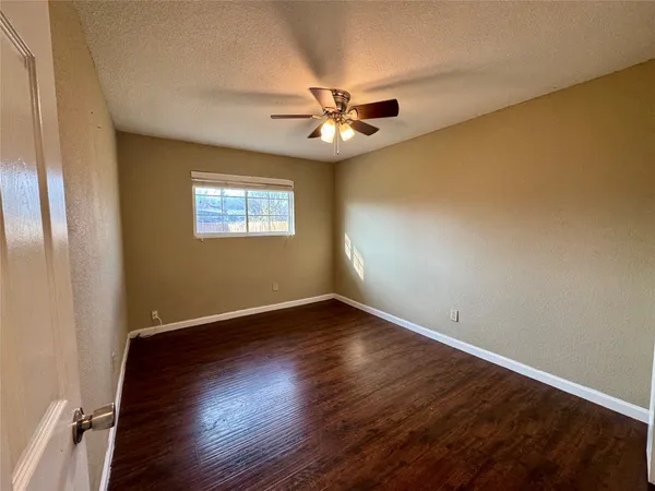 an empty room with wooden floor fan and windows