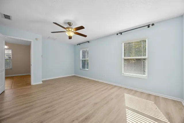 a view of empty room with wooden floor and fan