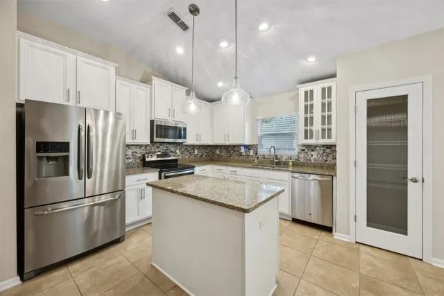 a large kitchen with granite countertop a large kitchen island white cabinetry and a granite counter tops