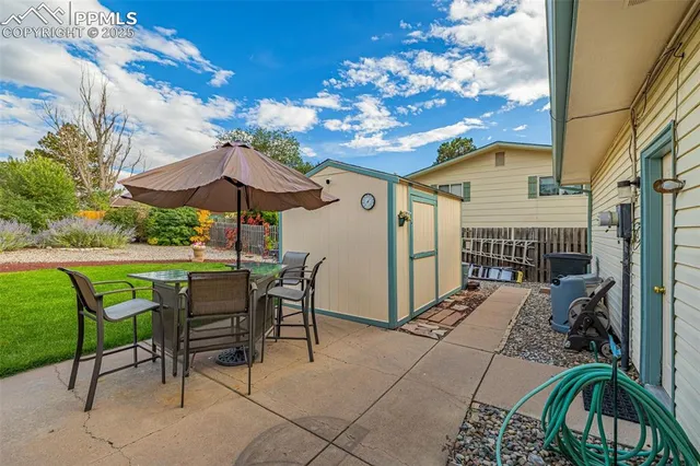 a view of a patio with table and chairs under an umbrella with a small yard