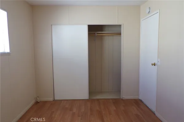 a view of an empty room with wooden floor & closet