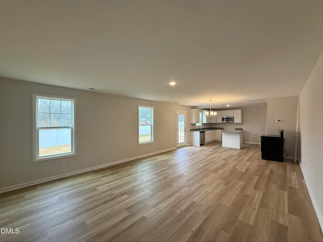 a view of empty room with wooden floor and window