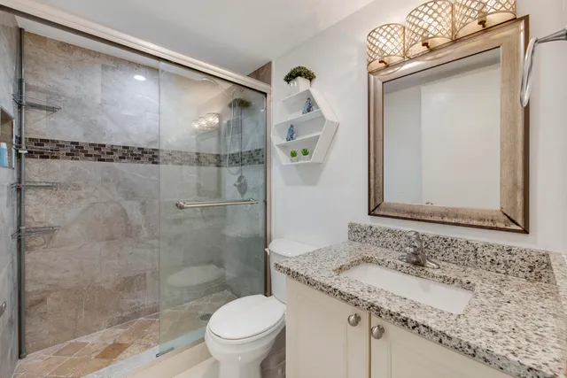 a bathroom with a granite countertop sink toilet and shower
