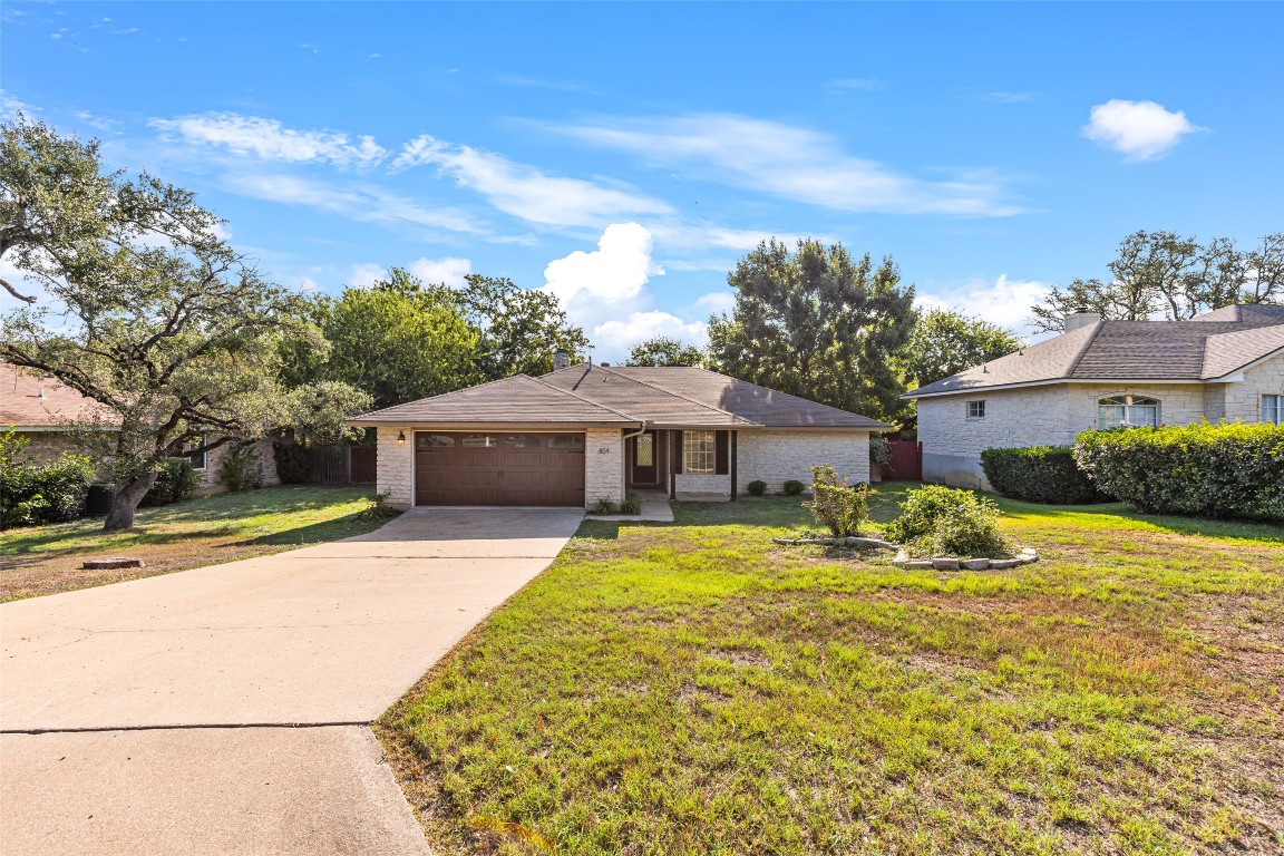 Ranch-style house with driveway, an attached garage, and brick siding