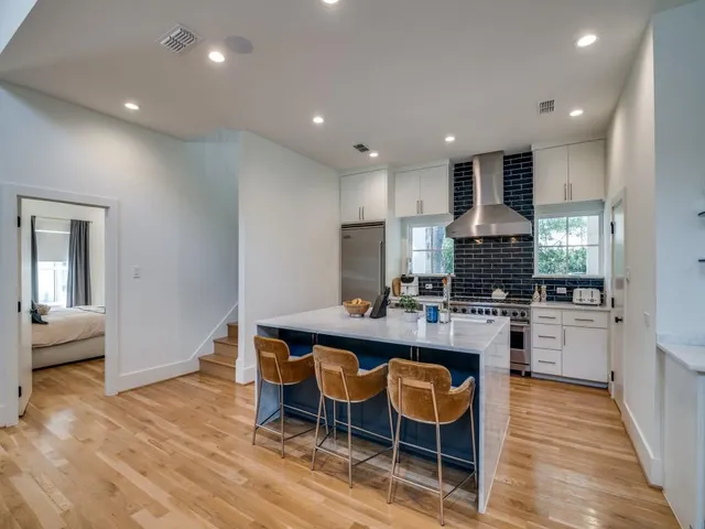 a kitchen with a dining table chairs wooden floor appliances and cabinets