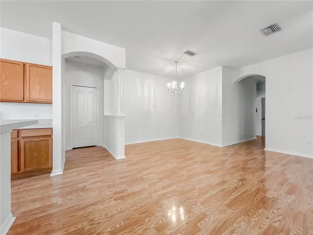 an empty room with wooden floor and ceiling fan