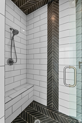 1426 South 1450th Street West Mapleton, UT 84664 - Photo 16 of 50 Shower featuring white subway tile walls, a built-in bench, black herringbone floor tile, a black herringbone accent column, and a glass shower door with a polished chrome handle