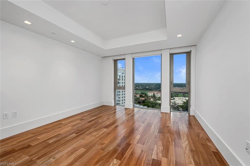 6897 Grenadier Boulevard, Unit 1804 Naples, FL 34108 - Photo 16 of 30 a view of an empty room with wooden floor and a window