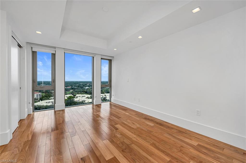 6897 Grenadier Boulevard, Unit 1804 Naples, FL 34108 - Photo 17 of 30 a view of an empty room with wooden floor and a window