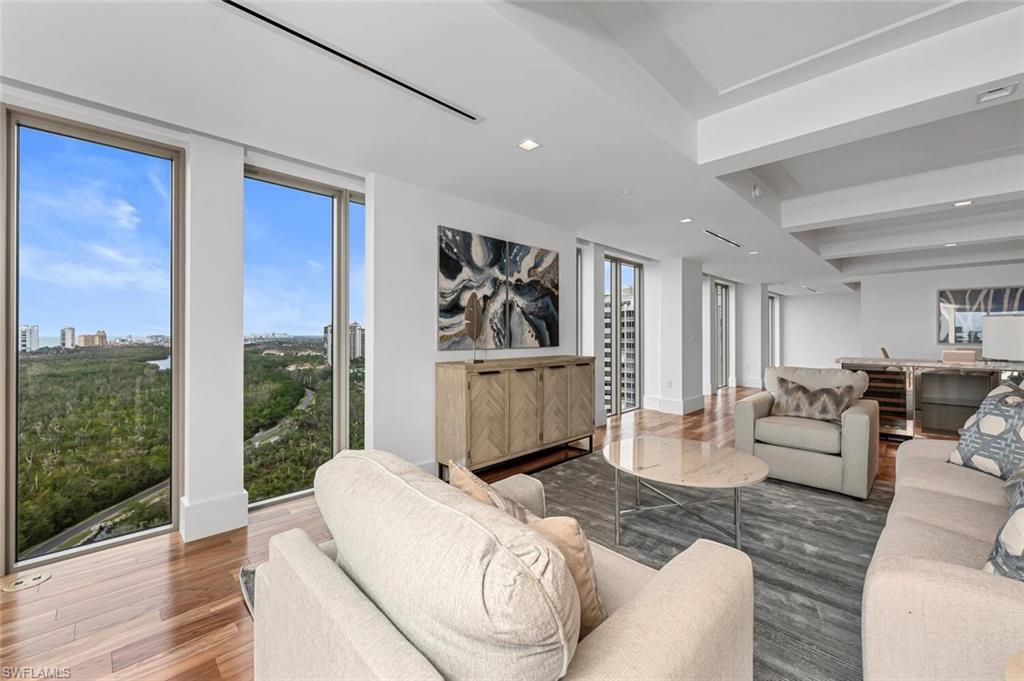 6897 Grenadier Boulevard, Unit 1804 Naples, FL 34108 - Photo 8 of 30 a living room with furniture wooden floor and a floor to ceiling window