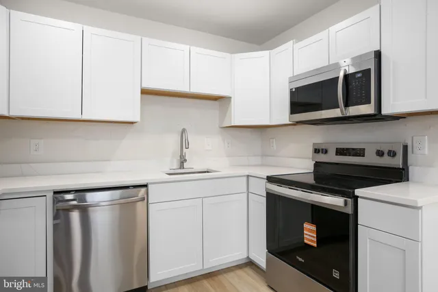 a kitchen with stainless steel appliances granite countertop white cabinets a microwave a sink and a counter space