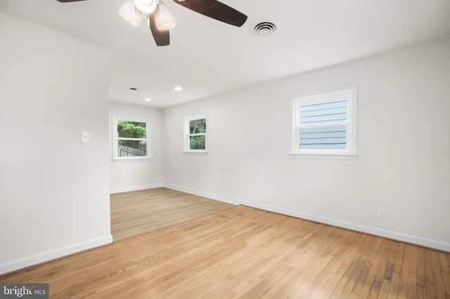 an empty room with wooden floor cabinet and windows