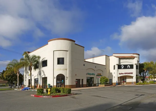 a front view of a building with streets and trees