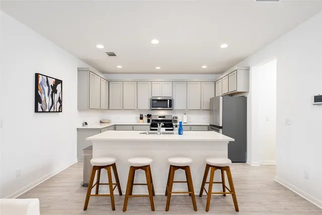 a living room with furniture kitchen view and a wooden floor