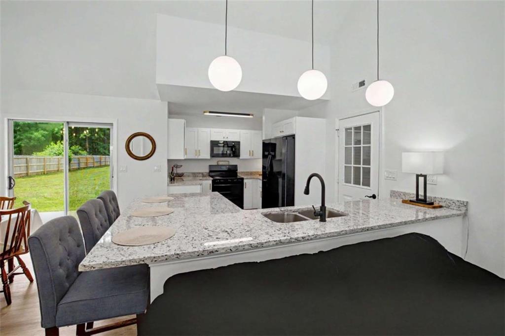 146 Jeb Stuart Drive Newnan, GA 30265 - Photo 12 of 33 a kitchen with granite countertop a stove a sink dishwasher a dining table and chairs with wooden floor