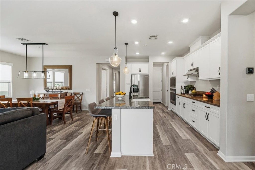 32937 Marin Fields Road Winchester, CA 92596 - Photo 12 of 47 a large kitchen with lots of counter space dining table and stainless steel appliances
