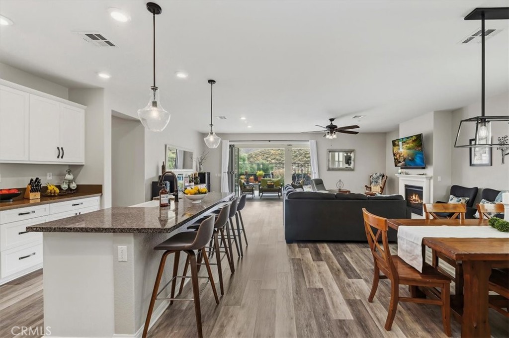 32937 Marin Fields Road Winchester, CA 92596 - Photo 5 of 47 a kitchen with stainless steel appliances granite countertop a stove a refrigerator a kitchen island a dining table and chairs with wooden floor