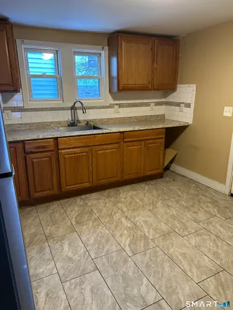 a kitchen with granite countertop a sink a stove a cabinets and a window