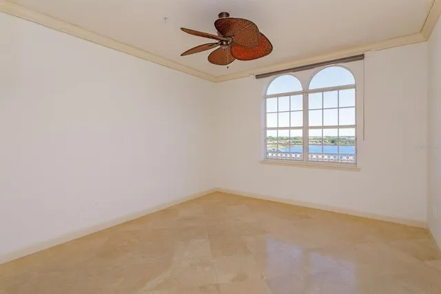 an empty room with chandelier fan and windows