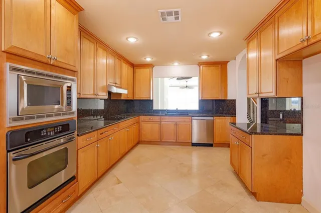 a large kitchen with stainless steel appliances granite countertop a stove a sink and a microwave