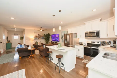 a kitchen with stainless steel appliances kitchen island granite countertop a stove a sink dishwasher a dining table and chairs with wooden floor