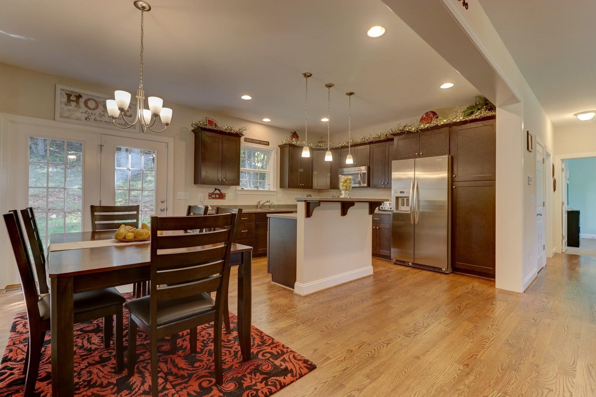 a kitchen with stainless steel appliances kitchen island granite countertop a dining table chairs and a refrigerator