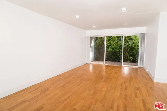 a view of empty room with wooden floor and windows