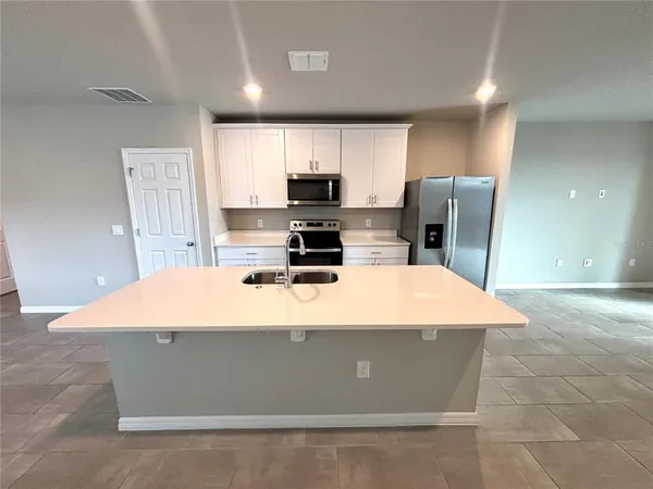 a room with kitchen island a stove a refrigerator a sink and a stove