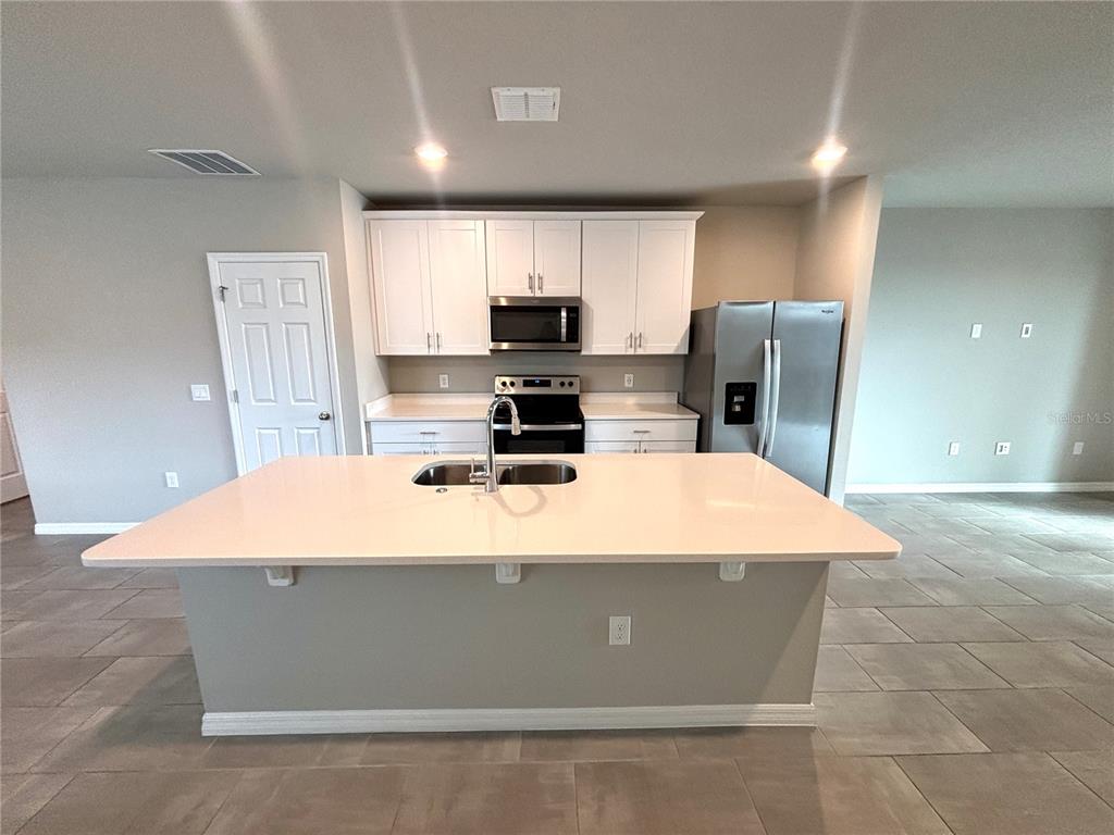 828 Rivers Crossing Street Clermont, FL 34714 - Photo 3 of 17 a room with kitchen island a stove a refrigerator a sink and a stove