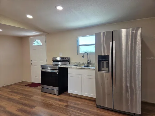a kitchen with stainless steel appliances wooden floor and a sink