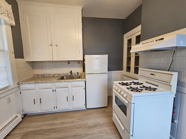 a kitchen with granite countertop a sink stove and refrigerator
