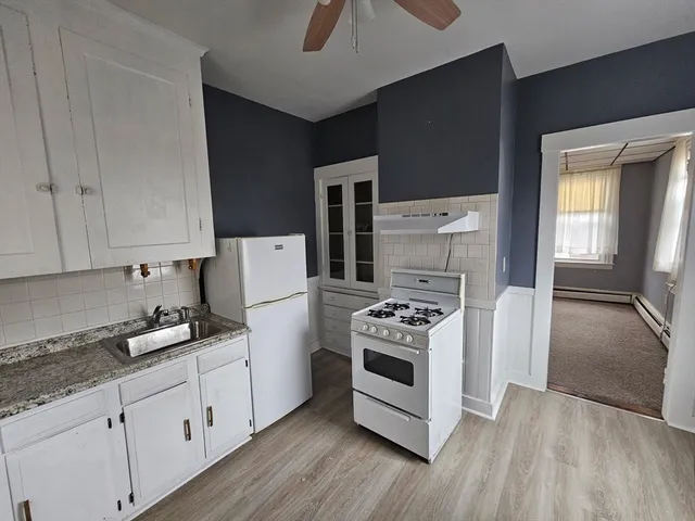 a kitchen with granite countertop a stove a sink and a refrigerator