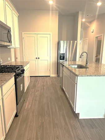 a kitchen with stainless steel appliances granite countertop a stove a sink dishwasher and a refrigerator with wooden floor