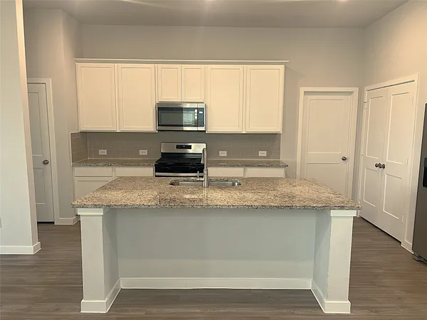 a kitchen with granite countertop a sink a stove a microwave and wooden cabinets