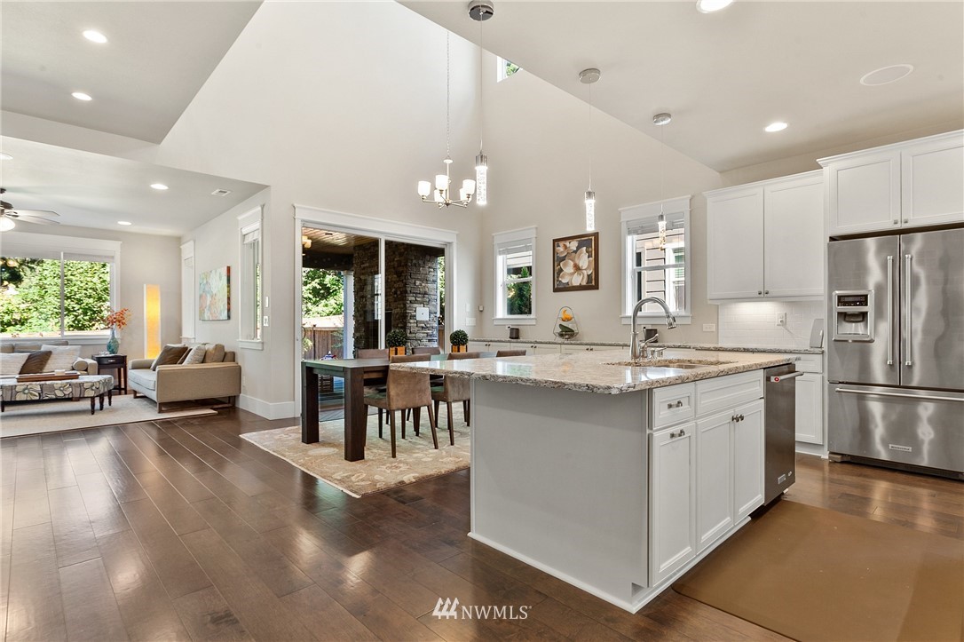 323 Field Place Southeast Renton, WA 98059 - Photo 3 of 40 a kitchen with stainless steel appliances kitchen island granite countertop a refrigerator a oven a dining table and chairs with wooden floor