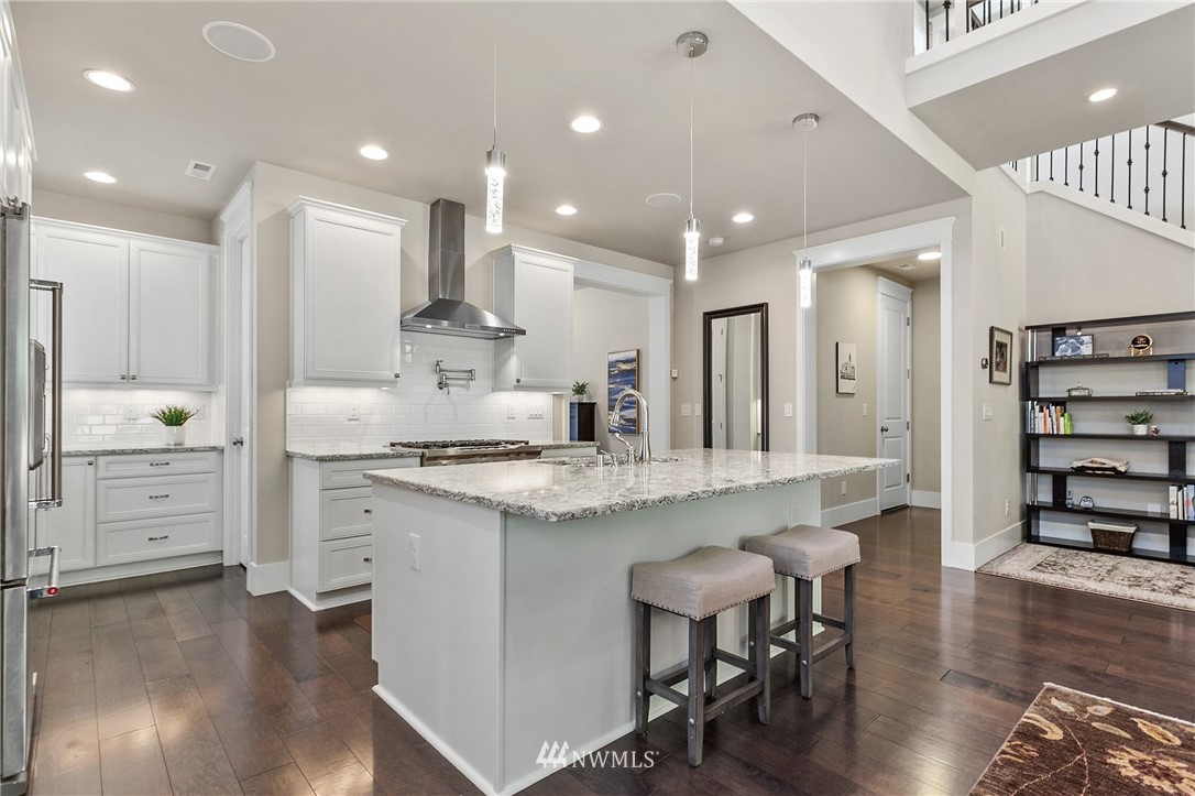 323 Field Place Southeast Renton, WA 98059 - Photo 4 of 40 a large kitchen with white cabinets a stove a sink and a chairs