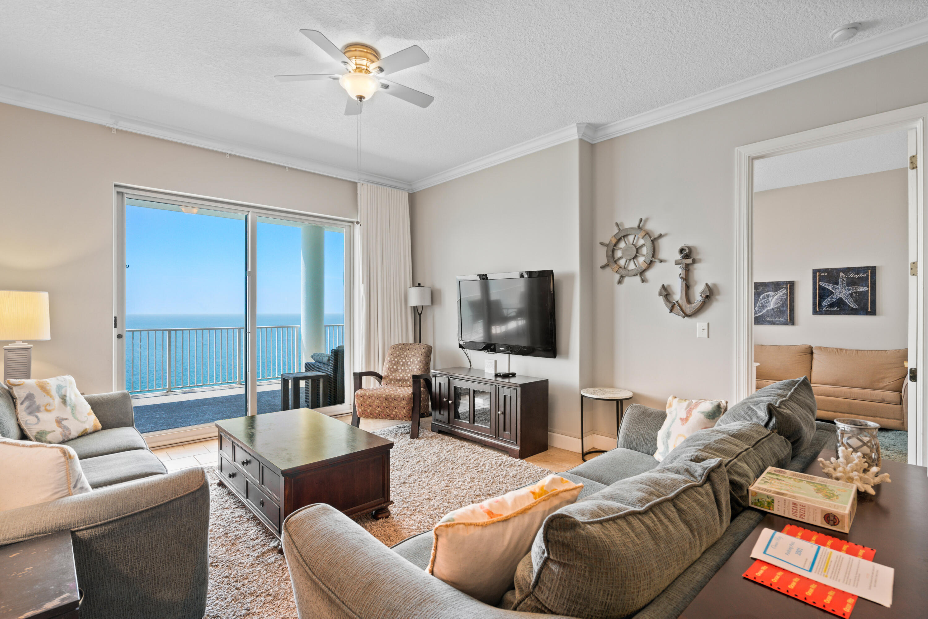 10611 Front Beach Road, Unit 2001 Panama City Beach, FL 32408 - Photo 18 of 49 a living room with furniture a ceiling fan and a flat screen tv