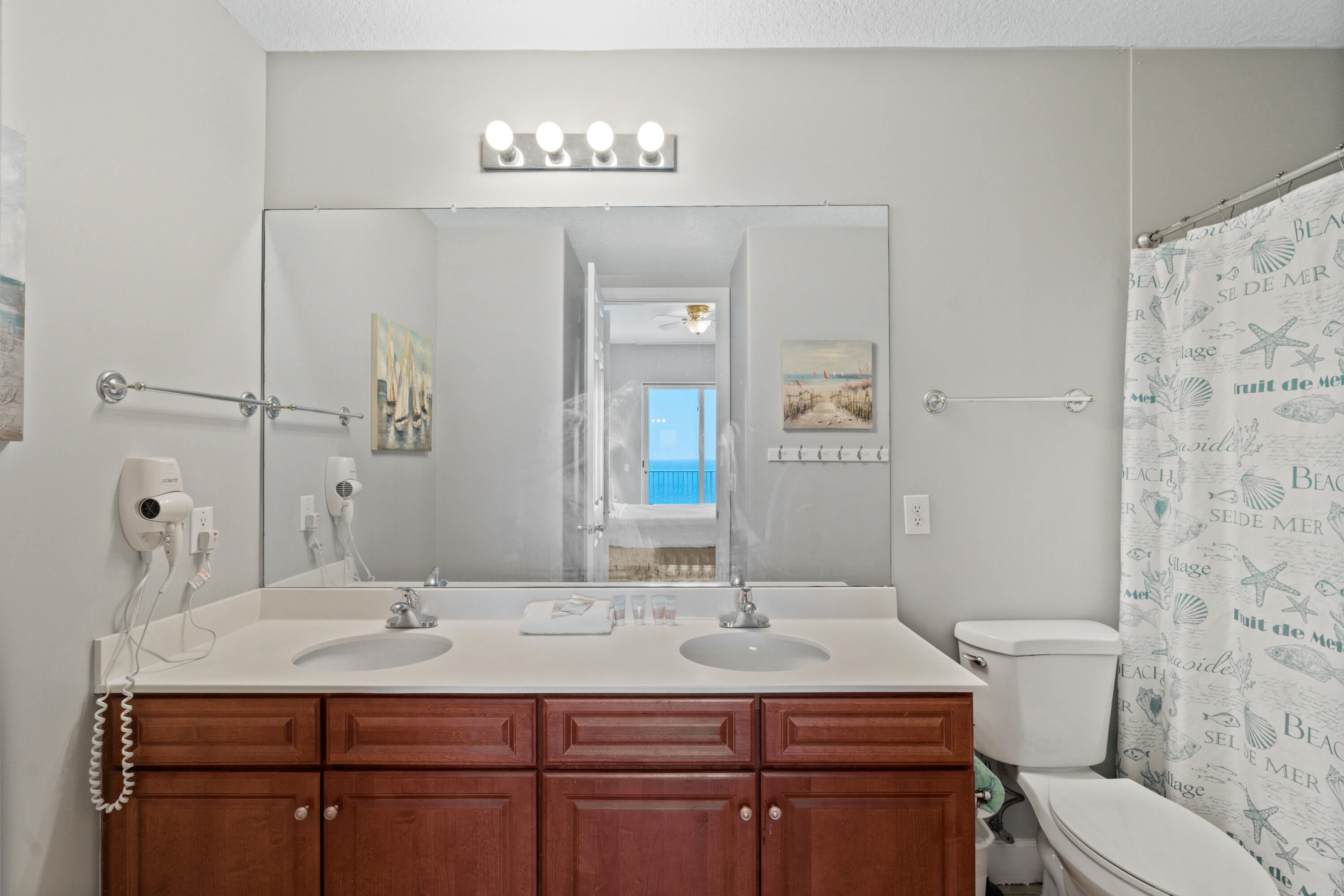 10611 Front Beach Road, Unit 2001 Panama City Beach, FL 32408 - Photo 22 of 49 a bathroom with a granite countertop sink a toilet and mirror