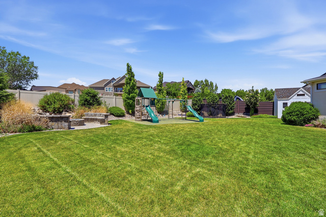 10676 Urban Rdg Cove South Jordan, UT 84095 - Photo 45 of 48 Expansive green lawn with a built-in stone fire pit and seating area