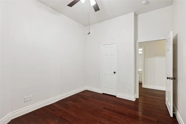 an empty room with wooden floor chandelier fan and windows