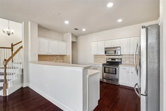 a kitchen with white cabinets and appliances