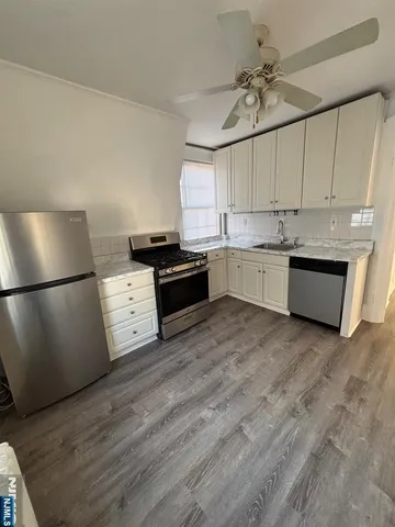 a kitchen with granite countertop a sink cabinets stainless steel appliances and a counter top space