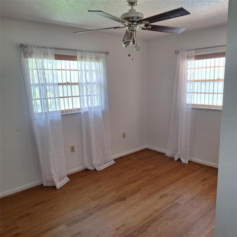 514 Spring Oaks Boulevard Altamonte Springs, FL 32714 - Photo 9 of 16 an empty room with wooden floor fan and windows